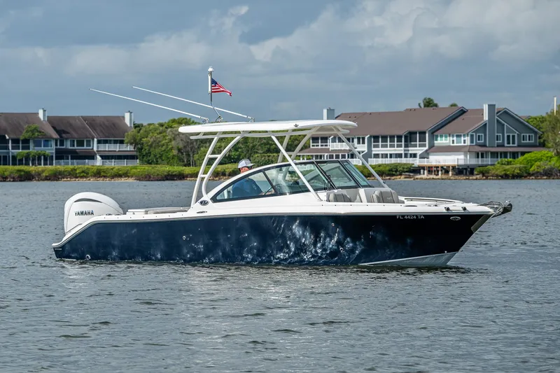 Slide: The Image of 2021 Pursuit DC 246 Dual Console boat on water, with buildings in the background. - 9