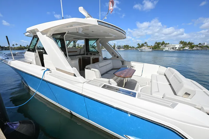 Slide: The Image of 2023 Tiara Yachts 48 LS, luxury boat docked, blue hull, spacious seating, sunny day. - 14