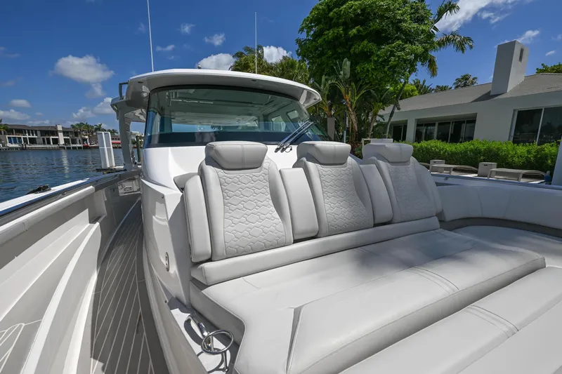 Slide: The Image of 2023 Tiara Yachts 48 LS luxury boat with plush seating, docked by waterfront homes. - 23