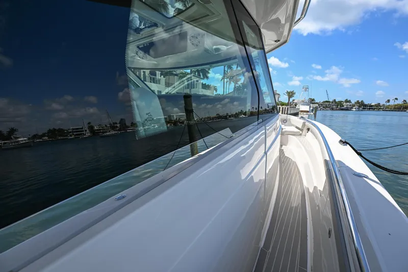 Slide: The Image of 2023 Tiara Yachts 48 LS, sleek design, docked by calm waters under a clear blue sky. - 25