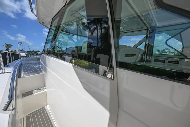 Slide: The Image of 2023 Tiara Yachts 48 LS, sleek exterior design with reflective windows, docked under a clear blue sky. - 27
