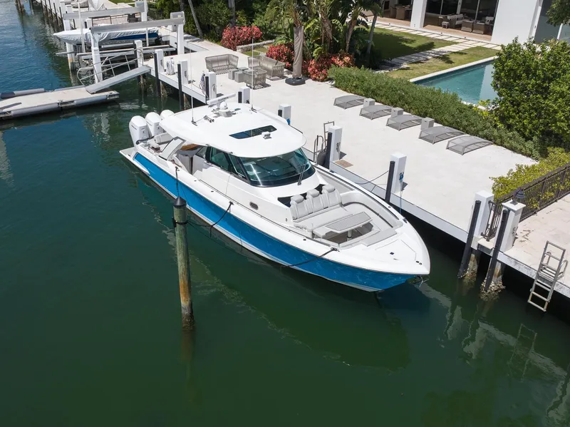 Slide: The Image of 2023 Tiara Yachts 48 LS docked by a luxurious waterfront property. - 3