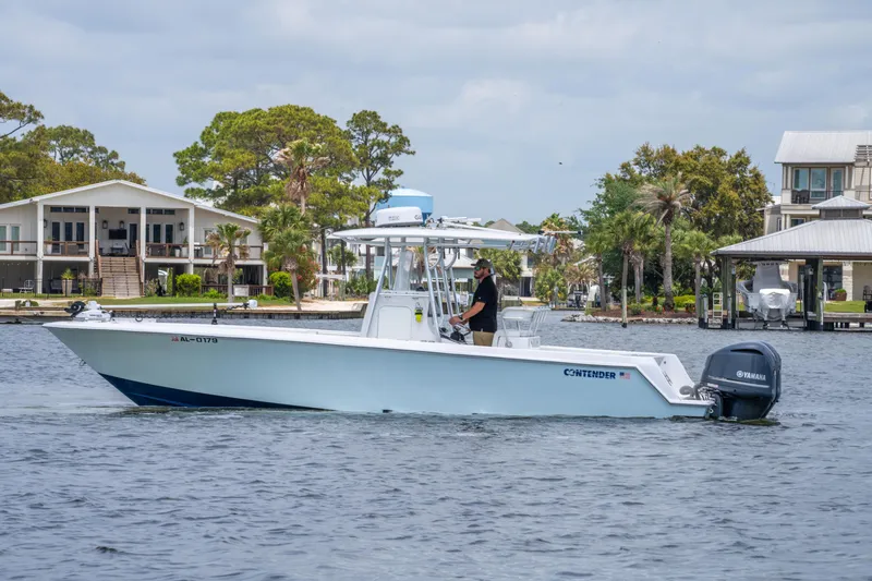 Slide: The Image of 2014 Contender 30st boat cruising on a calm waterway near waterfront homes. - 1