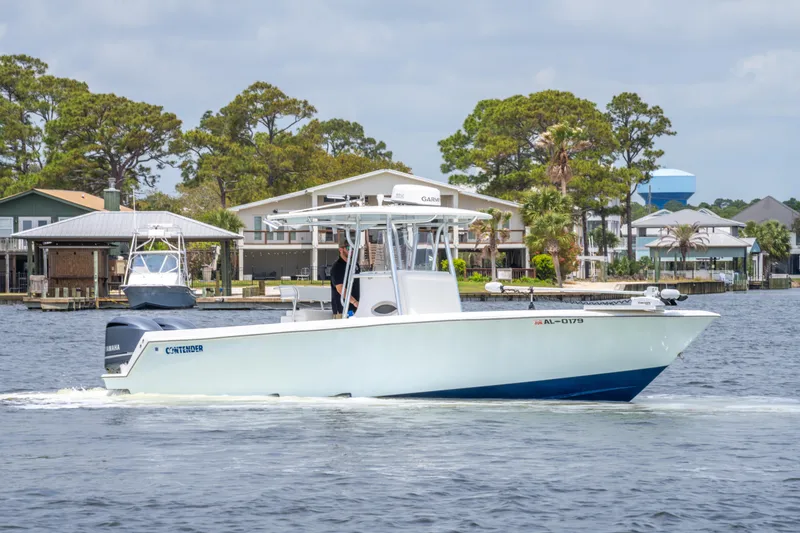 Slide: The Image of 2014 Contender 30st boat cruising on a calm waterway near waterfront homes. - 11