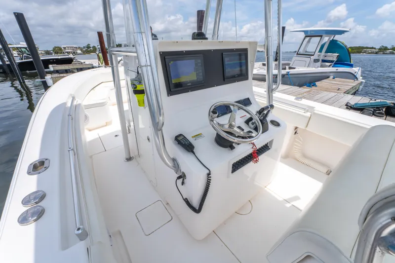 Slide: The Image of 2014 Contender 30st boat cockpit with dual screens and steering wheel, docked by the water. - 19