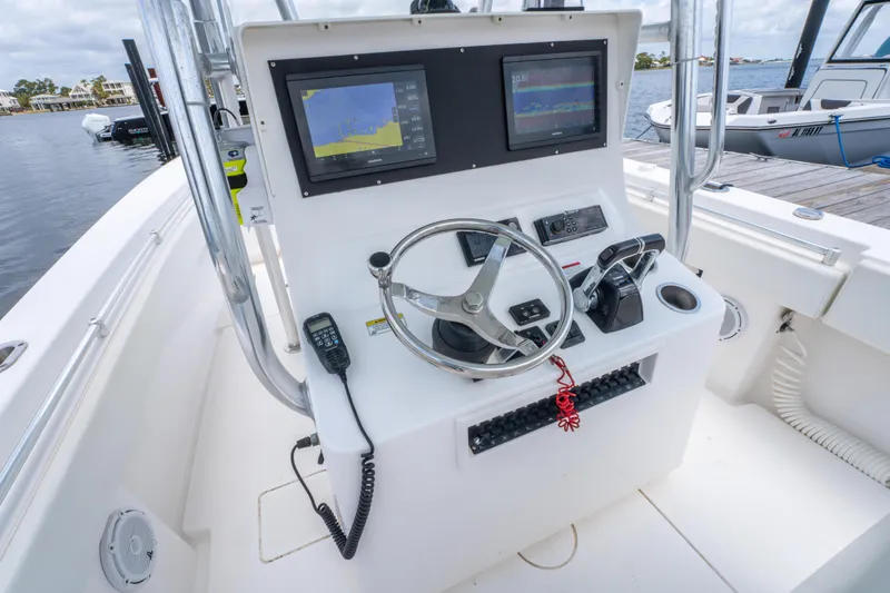 Slide: The Image of 2014 Contender 30st boat console with dual screens and steering wheel, docked by the water. - 23