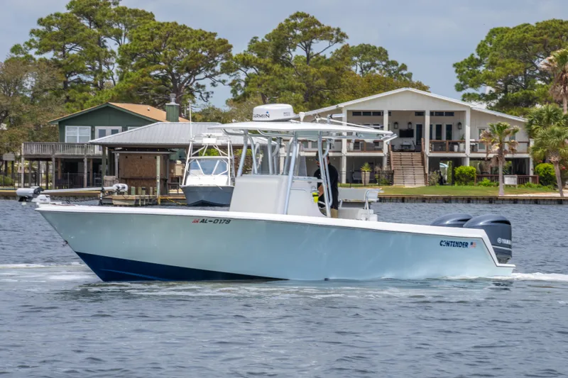 Slide: The Image of 2014 Contender 30st boat cruising on a lake near waterfront homes. - 5