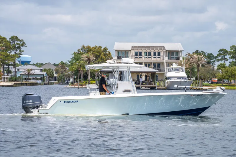 Slide: The Image of 2014 Contender 30st boat cruising on a calm waterway near waterfront homes. - 9
