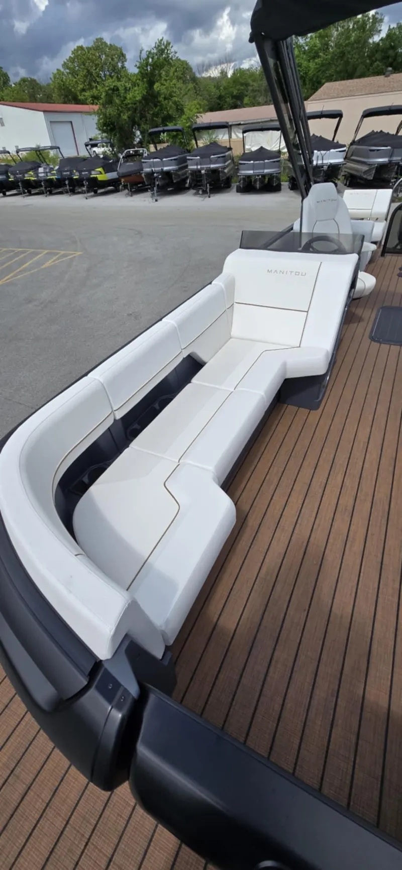 Slide: The Image of 2025 Manitou Explore boat with sleek white seating on a wooden deck. - 13