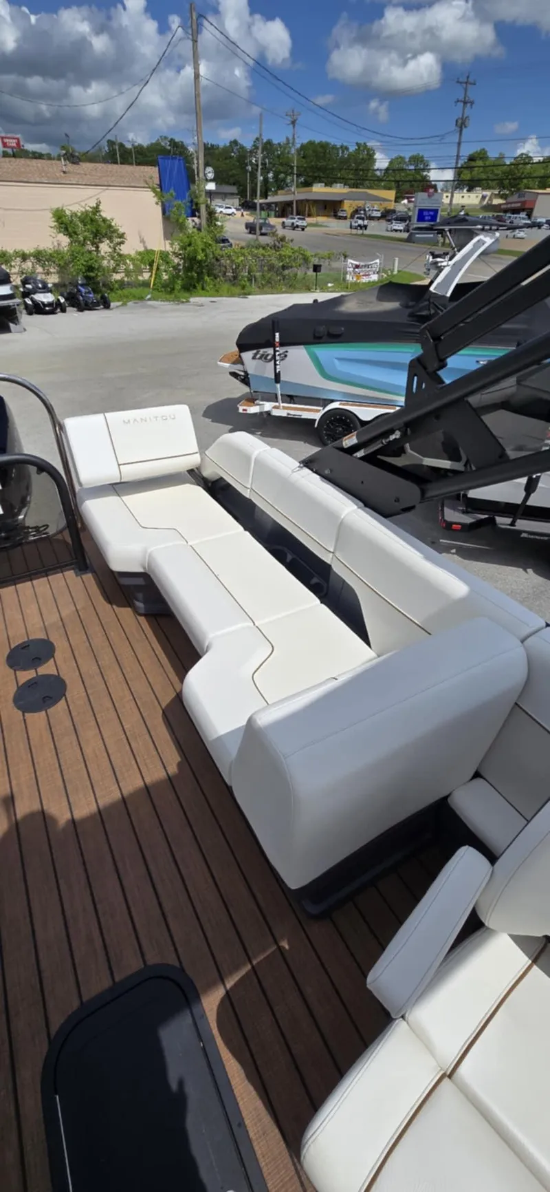 Slide: The Image of 2025 Manitou Explore boat with white seating and wooden deck, under a partly cloudy sky. - 18