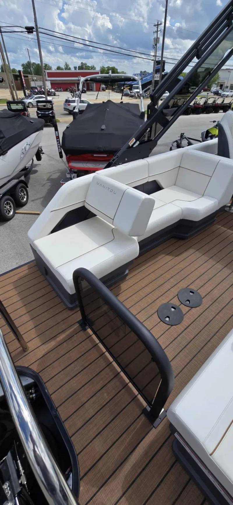 Slide: The Image of 2025 Manitou Explore boat with white seating and wooden deck, displayed outdoors. - 22