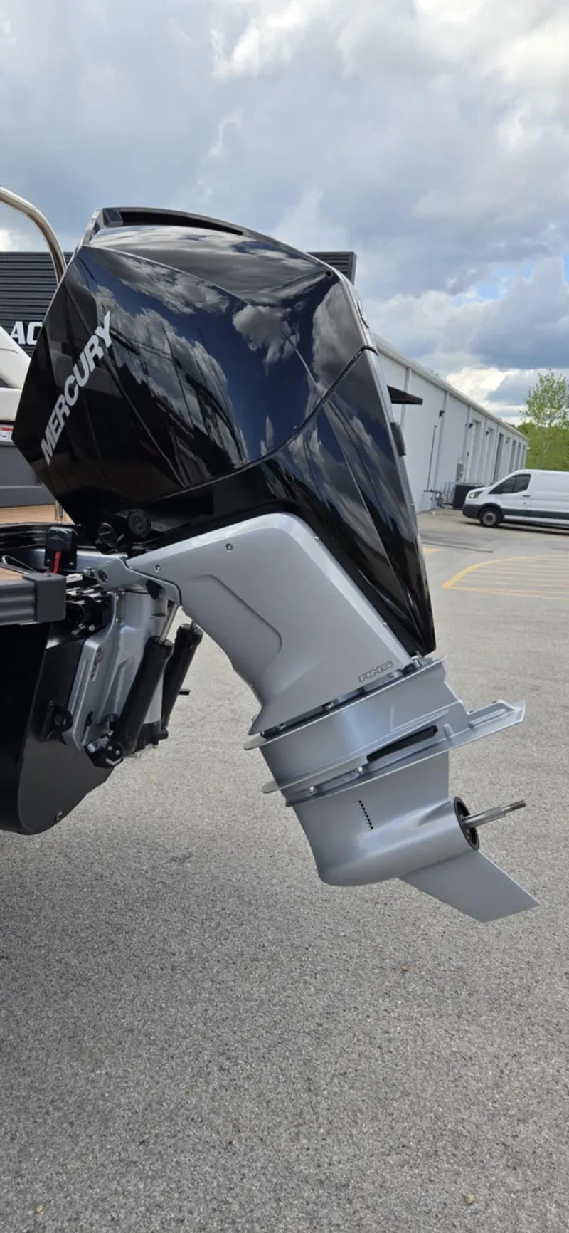 Slide: The Image of 2025 Manitou Explore boat with Mercury outboard motor, parked outdoors. - 8