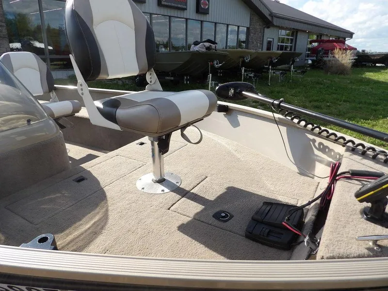 Slide: The Image of 2006 Lowe FM165SC boat interior with seating and controls, parked near a building. - 13