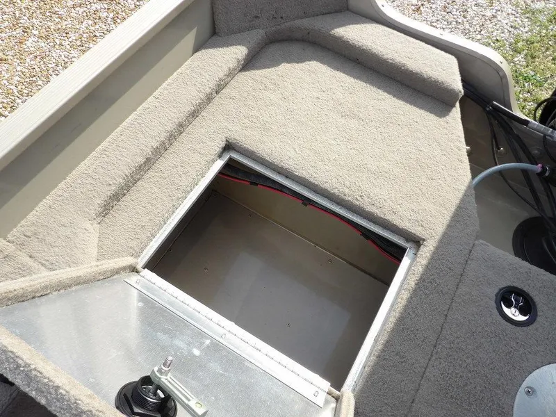 Slide: The Image of 2006 Lowe FM165SC boat storage compartment with open hatch, carpeted interior. - 28