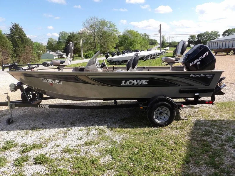 Slide: The Image of 2006 Lowe FM165SC fishing boat on trailer, featuring Mercury outboard motor, parked outdoors. - 34