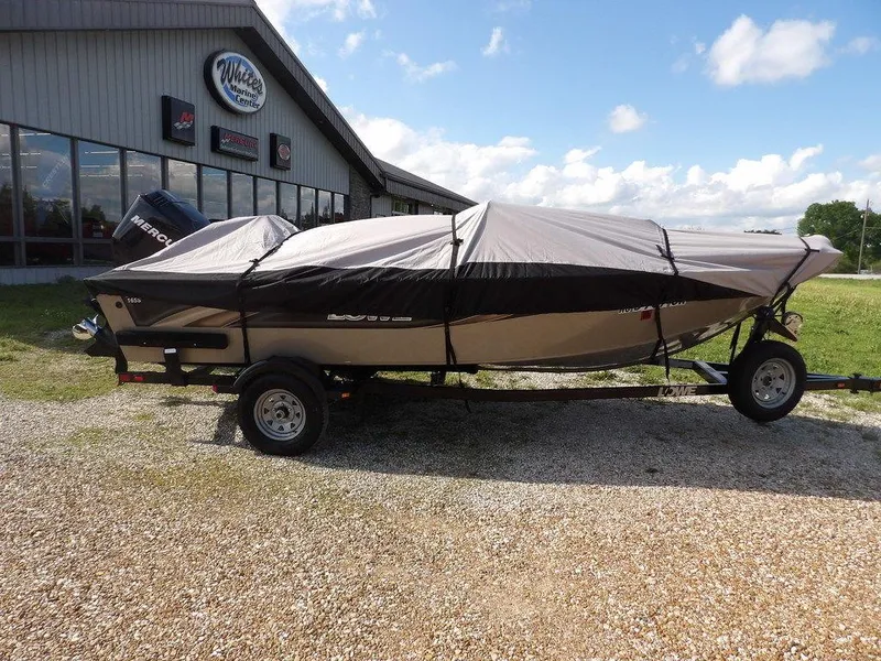 Slide: The Image of 2006 Lowe FM165SC boat covered on trailer, parked outside dealership under blue sky. - 38