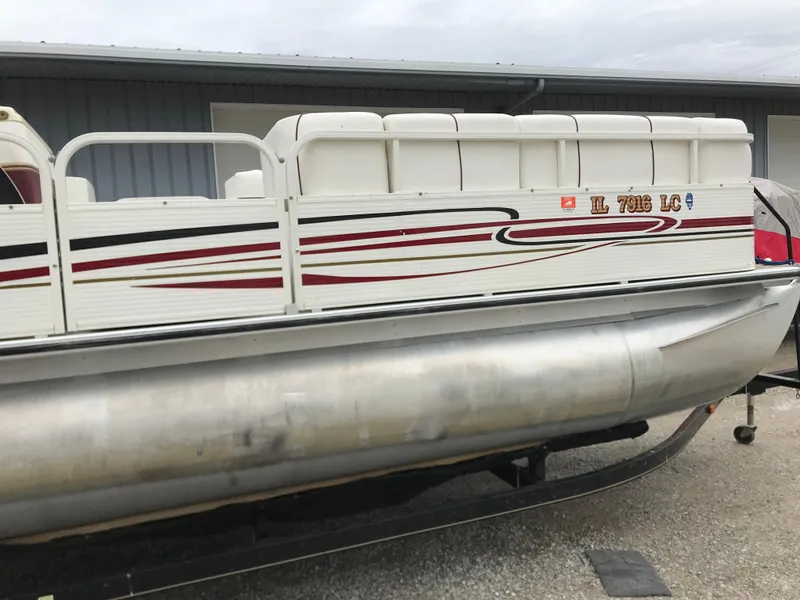 Slide: The Image of 2005 Bentley Pontoons 243 boat with white and red design, parked on a trailer. - 10