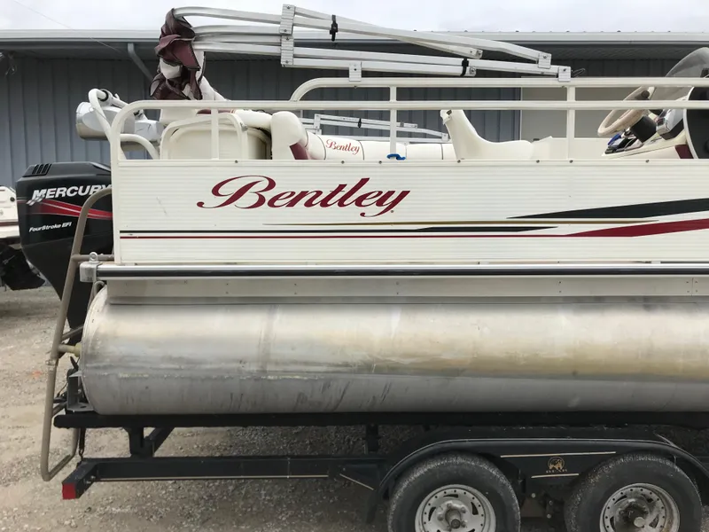 Slide: The Image of 2005 Bentley Pontoons 243 on trailer, side view with visible logo and Mercury outboard motor. - 11
