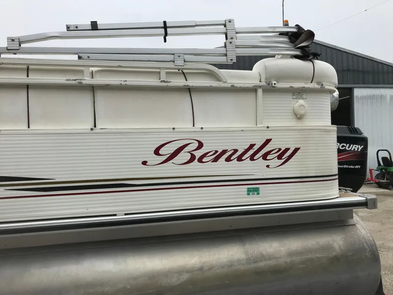 Slide: The Image of 2005 Bentley Pontoons 243 boat with visible logo and Mercury engine in the background. - 2