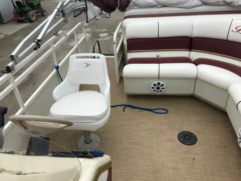 Slide: The Image of 2005 Bentley Pontoons 243 interior with white and maroon seating, steering chair, and deck. - 20