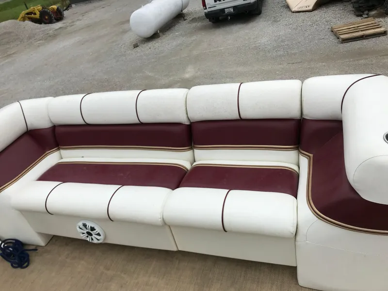 Slide: The Image of 2005 Bentley Pontoons 243 boat seating with white and maroon upholstery, outdoor setting. - 26