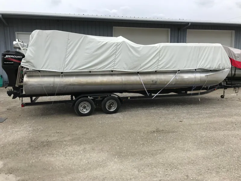 Slide: The Image of 2005 Bentley Pontoons 243 covered on trailer, parked outside a building. - 29