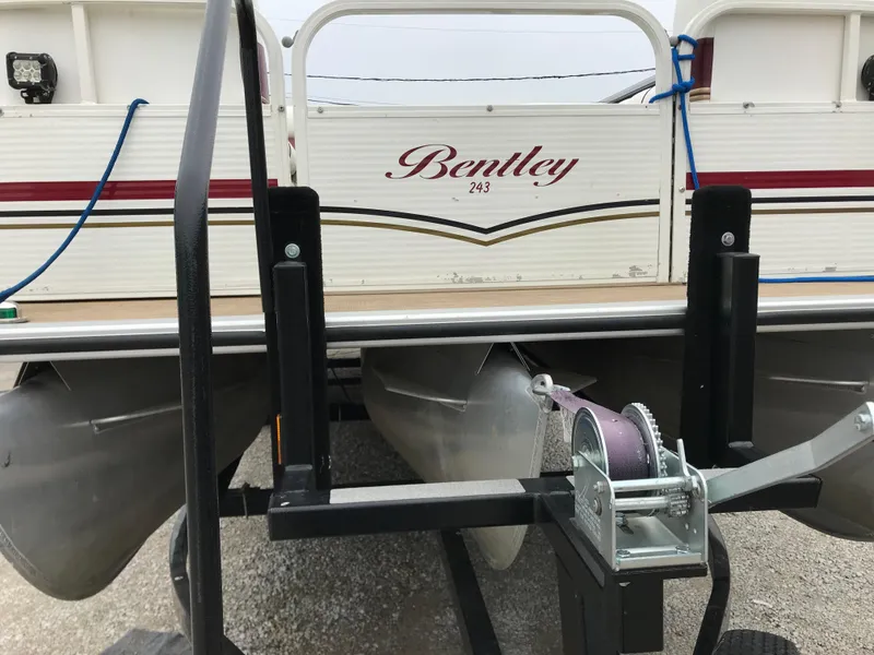 Slide: The Image of 2005 Bentley Pontoons 243 on trailer, showcasing boat's rear and winch system. - 3