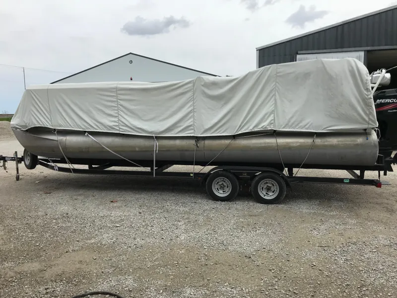 Slide: The Image of 2005 Bentley Pontoons 243 covered on trailer, parked outdoors near a building. - 30