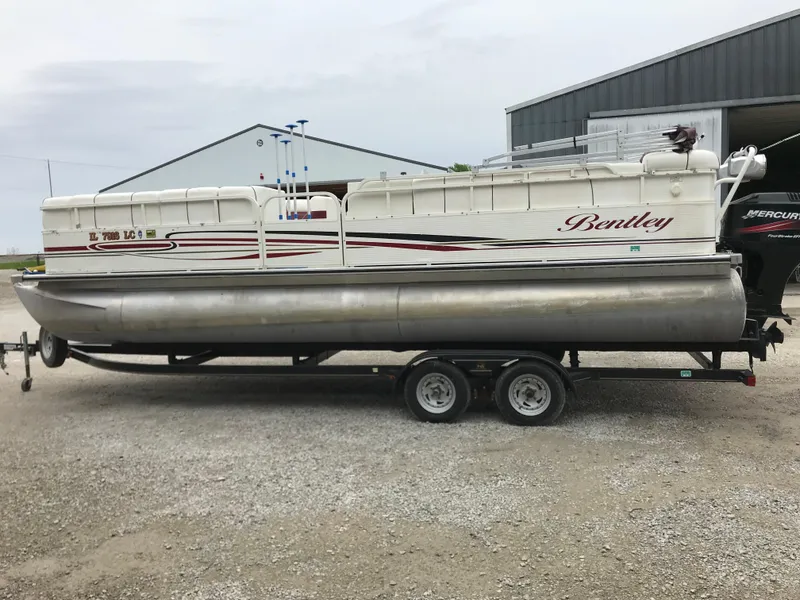 Slide: The Image of 2005 Bentley Pontoons 243 on trailer, parked outdoors near a metal building. - 6