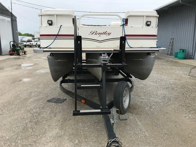 Slide: The Image of 2005 Bentley Pontoons 243 on trailer, parked outdoors near industrial buildings. - 9
