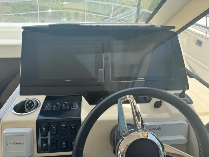 Slide: The Image of The cockpit of a Regal 38 XO yacht with two large screens and a steering wheel. - 9