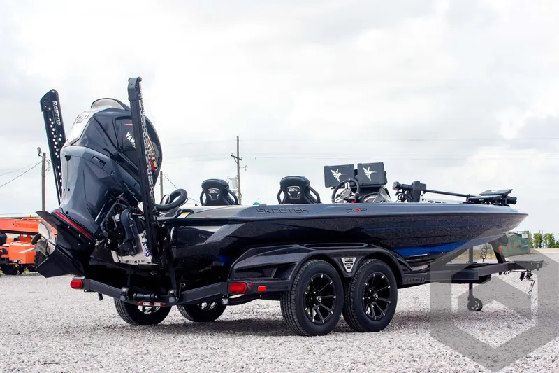 Slide: The Image of 2025 Skeeter FXR 21 Limited boat on trailer, rear view, parked on gravel. - 5
