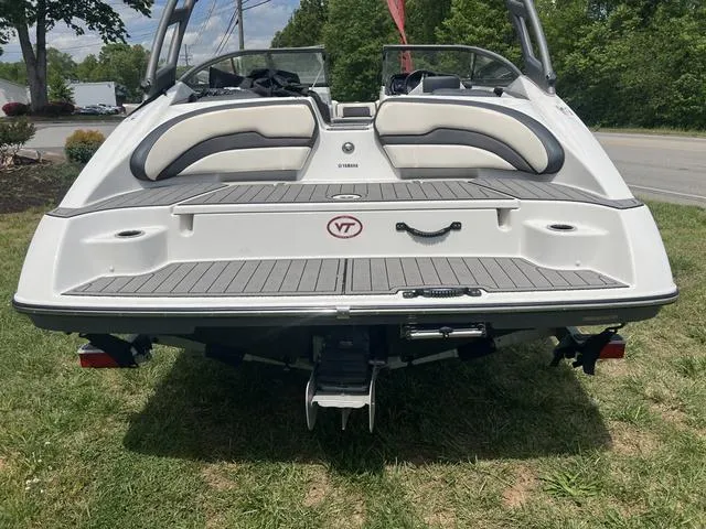 Slide: The Image of 2019 Yamaha Boats AR195, rear view, on grass, showcasing swim platform and seating. - 16