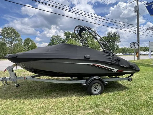 Slide: The Image of 2019 Yamaha AR195 boat on trailer, covered, parked on grass under cloudy sky. - 7
