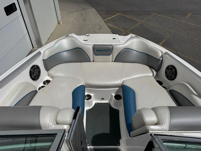 Slide: The Image of 2013 MasterCraft X35 boat interior with white and blue seating, cup holders, and speakers. - 8