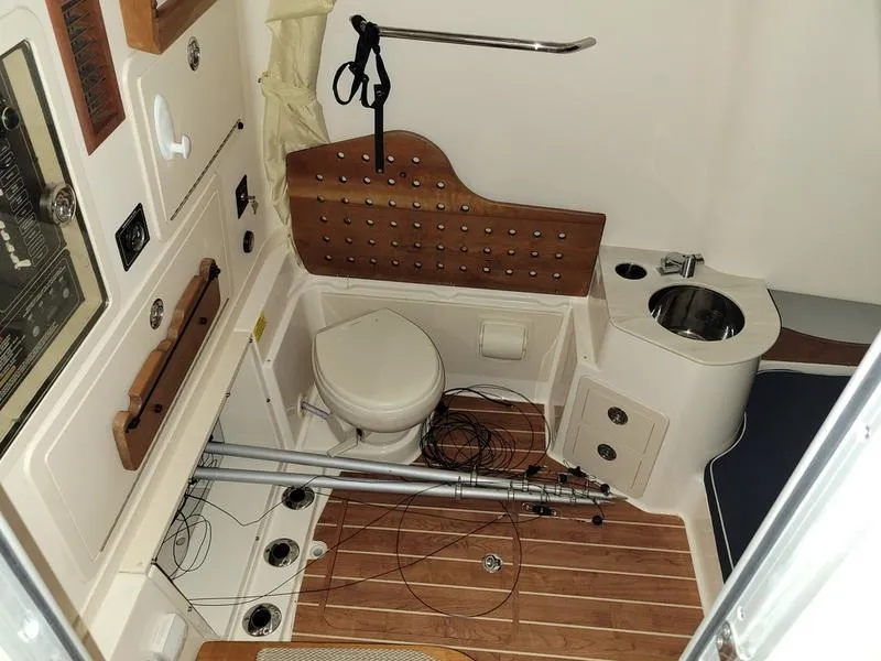 Slide: The Image of 2019 Grady-White 336 Canyon boat interior with toilet, sink, and fishing rods. - 9