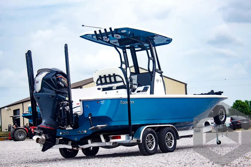 Slide: The Image of 2025 Tidewater 2410 Bay Max boat on trailer, blue hull, dual motors, parked outdoors. - 6
