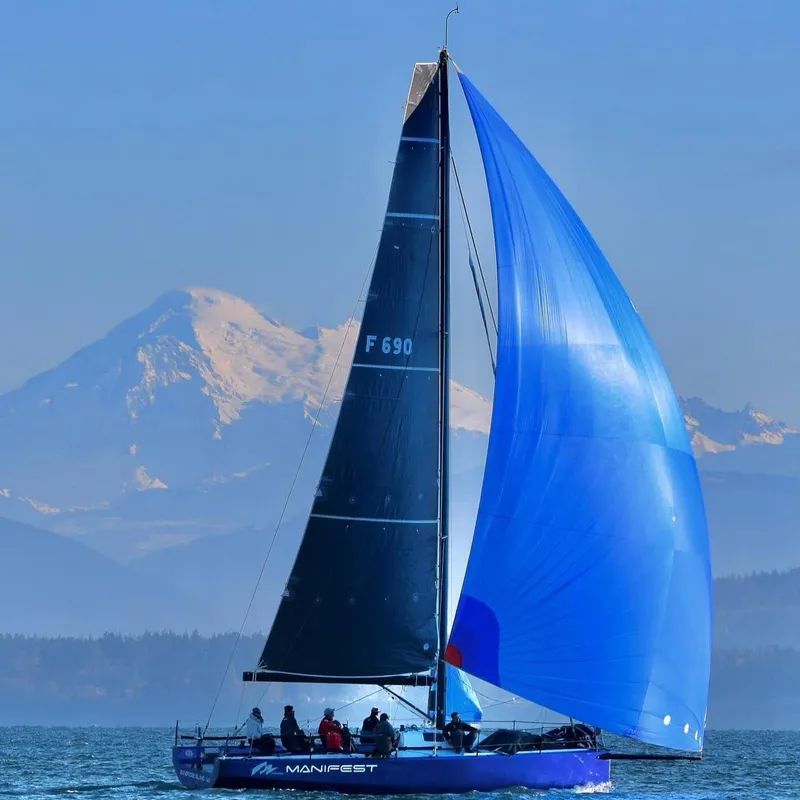 Slide: The Image of Sailboat "Manifest" on water with mountain backdrop, featuring blue spinnaker sail. - 18