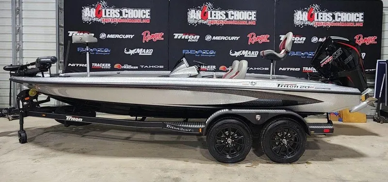 The Image of 2025 Triton 20XP Patriot boat on trailer, displayed indoors with branded backdrop. - 1