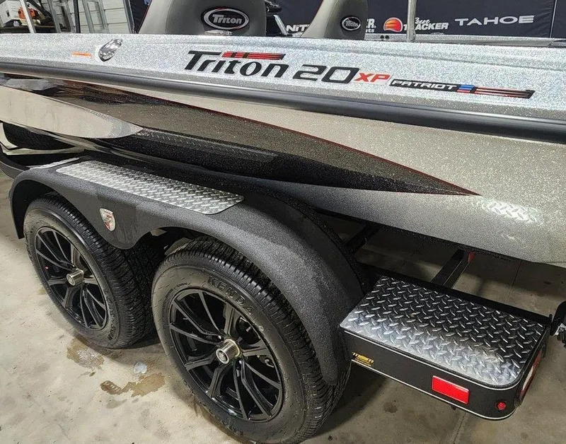 Slide: The Image of 2025 Triton 20XP Patriot boat with sleek design and dual black wheels. - 12