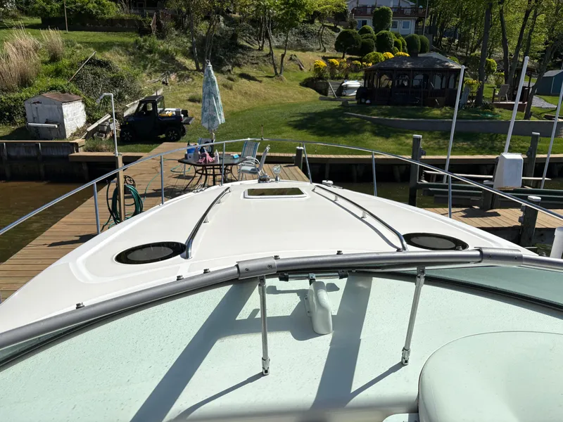 Slide: The Image of 2006 Sea Ray 320 Sundancer docked at a scenic waterfront with lush greenery. - 18