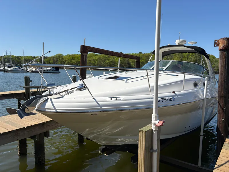 Slide: The Image of 2006 Sea Ray 320 Sundancer docked at a marina, surrounded by calm waters and sailboats. - 3