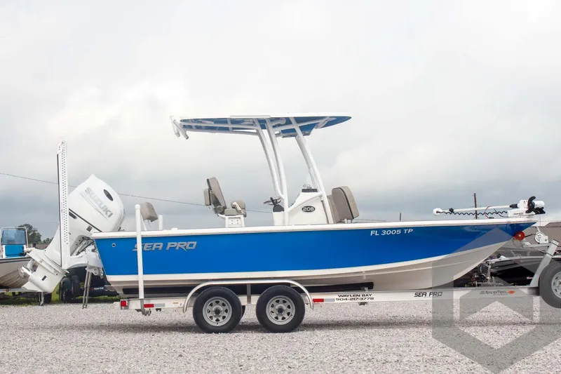 Slide: The Image of 2023 Sea Pro 208 Bay boat on trailer, blue hull, parked on gravel. - 10