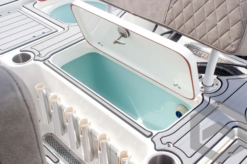 Slide: The Image of 2023 Sea Pro 208 Bay boat interior with open storage compartment and rod holders. - 47