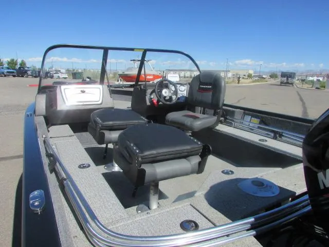 Slide: The Image of 2023 Tracker Pro Guide V16WT boat interior with seating and steering wheel, parked outdoors. - 6