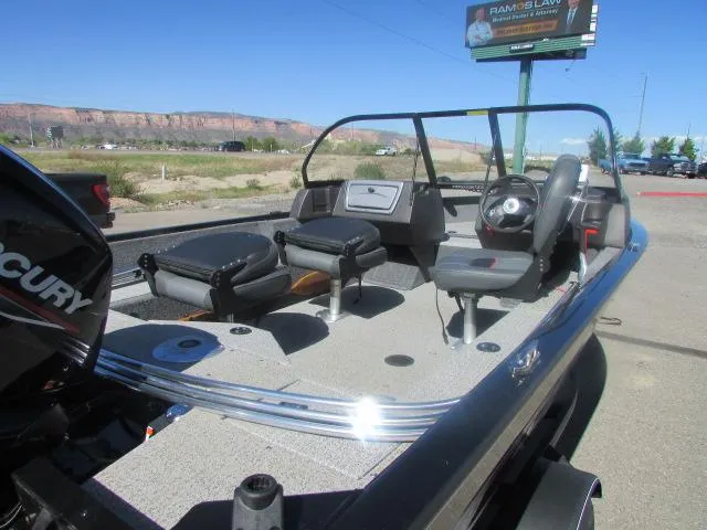 Slide: The Image of 2023 Tracker Pro Guide V16WT boat with seating and steering wheel, parked outdoors. - 7
