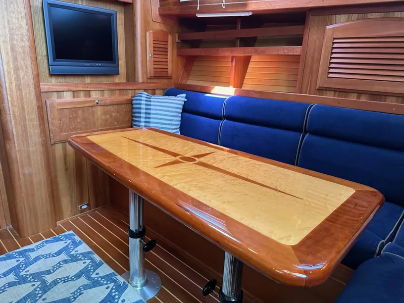 Slide: The Image of 2005 Sabre 38 Hardtop Express interior with wooden table, blue seating, and wall-mounted TV. - 24