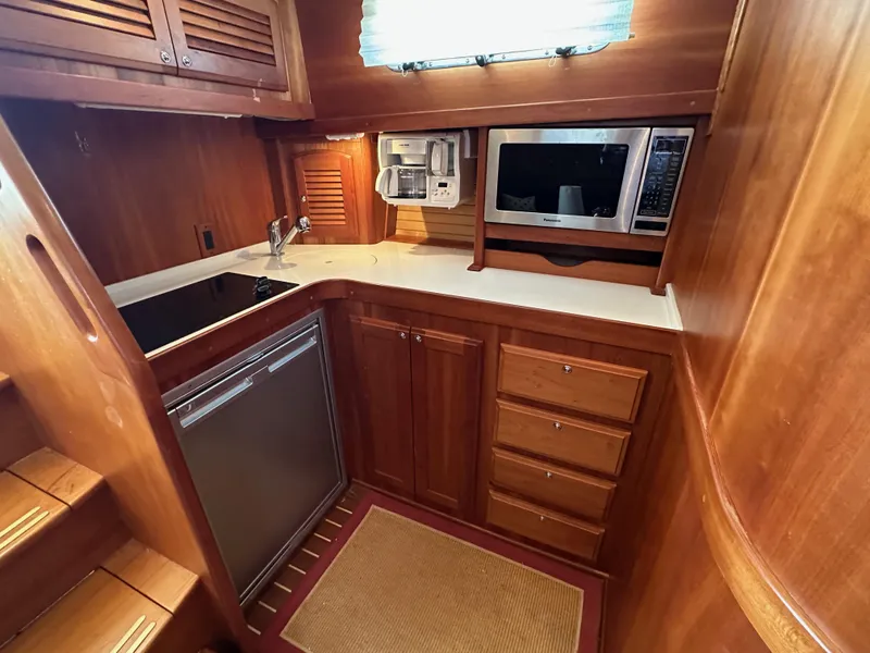 Slide: The Image of 2005 Sabre 38 Hardtop Express galley with wood cabinetry, microwave, and sink. - 28