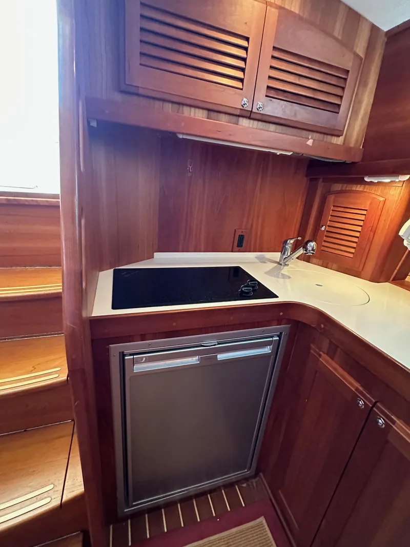 Slide: The Image of 2005 Sabre 38 Hardtop Express galley with wood cabinetry, stovetop, and compact refrigerator. - 30