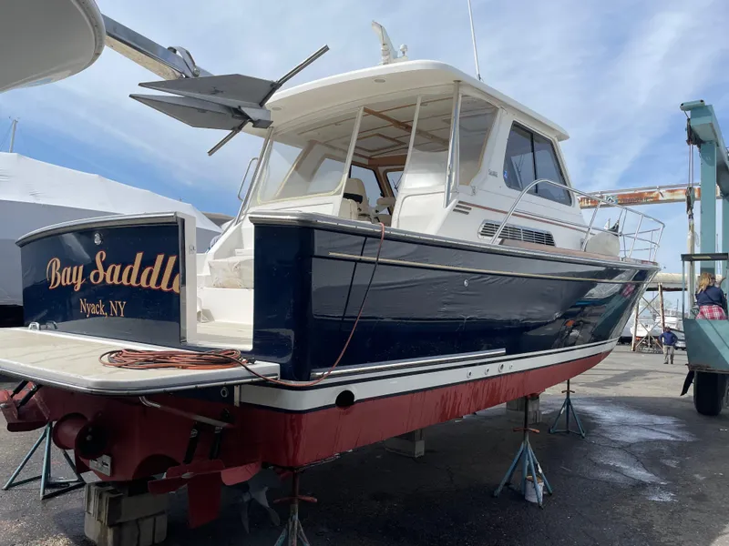Slide: The Image of 2005 Sabre 38 Hardtop Express boat on stands, blue hull, white cabin, docked outdoors. - 5